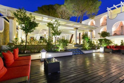 un patio esterno con divani rossi e piante di La Pineta Hotel Beach & Spa ad Acciaroli