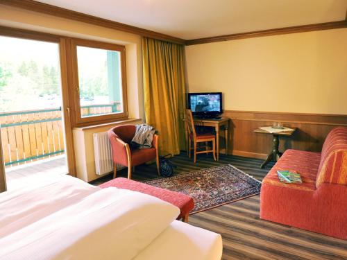 a hotel room with a bed and a desk and a television at Das Pfandler in Pertisau