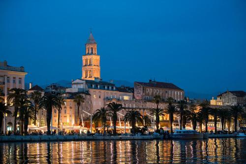 a city with a clock tower and palm trees at night at Heritage Hotel Antique Split in Split