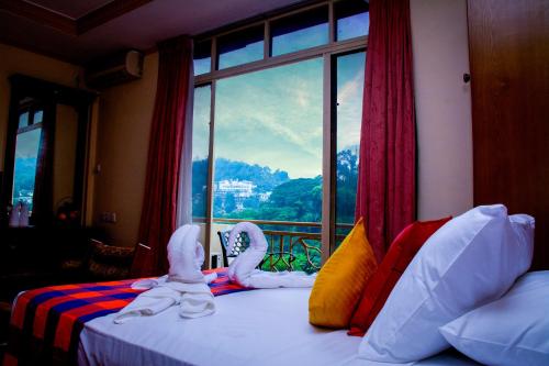 a bedroom with a bed with a view of a window at Hotel Lakefield in Kandy