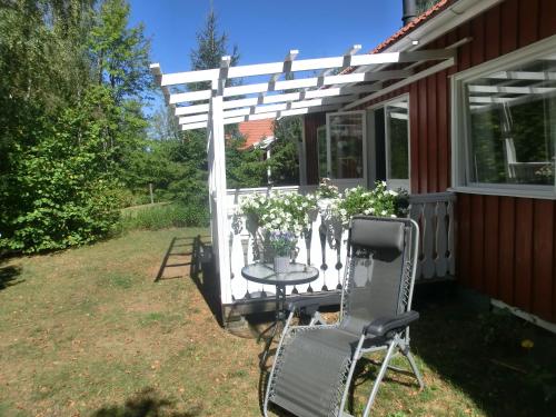 a white pergola on a house with a table and a chair at Björkslingan in Vimmerby