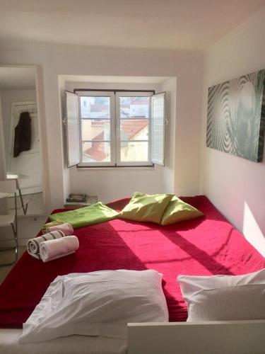 a bedroom with a large red bed with a window at Pequeno Hostel Studio in Lisbon