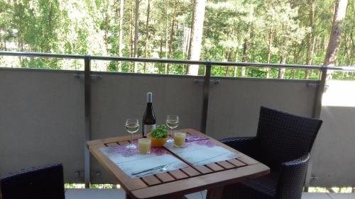 a table with a bottle of wine and two glasses at Apartament w Baltic Park in Stegna