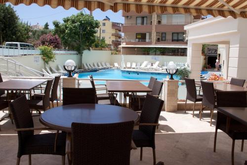 a restaurant with tables and chairs and a swimming pool at meryemana hotel in Didim