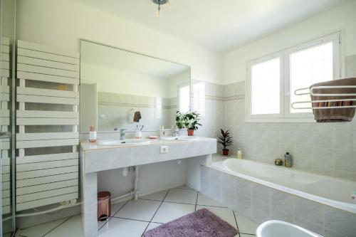 y baño con lavabo, bañera y espejo. en Villa Messanges (piscine & spa) en Messanges