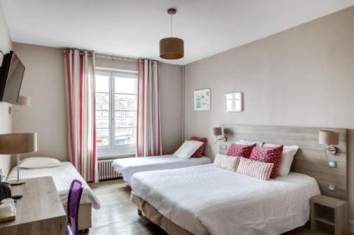 a hotel room with two beds and a window at Logis Hôtel Marguerite in Orléans