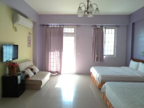 a hotel room with two beds and a couch at Vineyard Guest House in Taitung City