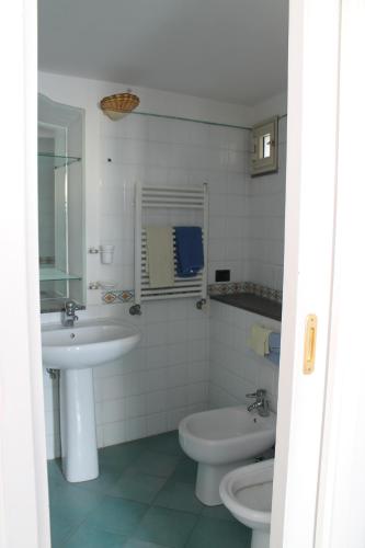 a white bathroom with a sink and a toilet at Attico del Cavaliere in Atrani