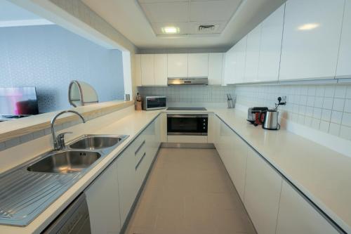 a kitchen with white cabinets and a sink at Stunning 5* 4BR-Oceanfront-Apartment in Dubai