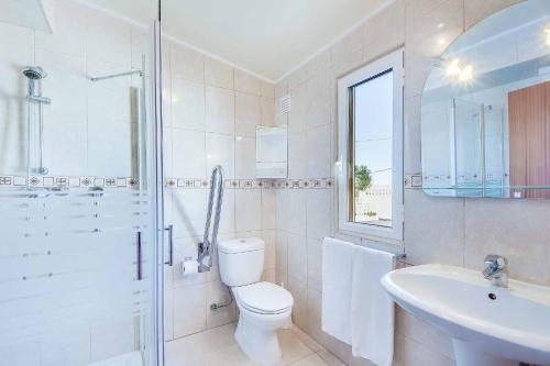 a white bathroom with a toilet and a sink at Villa Brigida in Albufeira