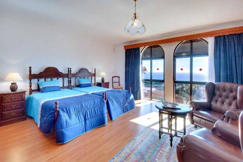 a bedroom with a blue bed and a couch at Villa Albuar in Albufeira
