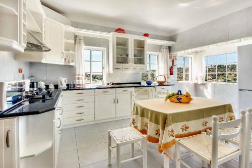 a kitchen with white cabinets and a table with chairs at Villa Sunny in Albufeira