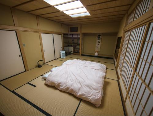 una grande camera con un letto bianco sul pavimento di 富谷緑水庵茶道体験 a Nanakita
