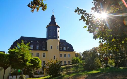 a large yellow building with a clock tower on a hill at Schlosshotel Domäne Walberberg in Bornheim