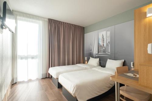 トゥールコワンにあるB&B HOTEL Lille Tourcoing Centreのベッド2台と窓が備わるホテルルームです。