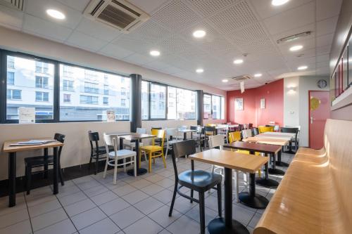 a dining room with tables and chairs and windows at B&B HOTEL Lille Tourcoing Centre in Tourcoing
