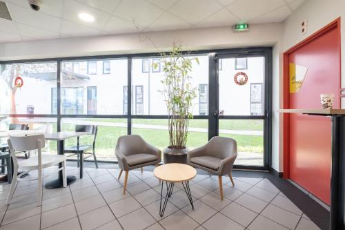 a waiting room with chairs and a table and a plant at B&B HOTEL Lille Tourcoing Centre in Tourcoing