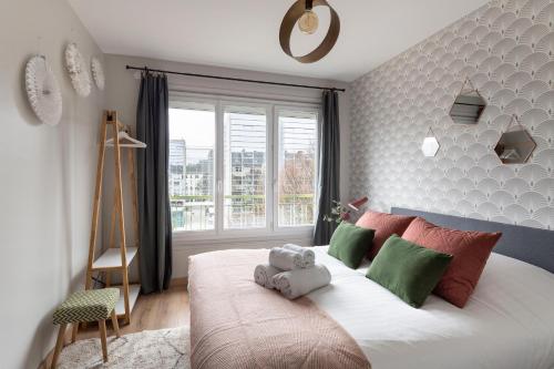 - une chambre dotée d'un grand lit avec des oreillers verts et rouges dans l'établissement Le Phenix by Cocoonr, à Nantes