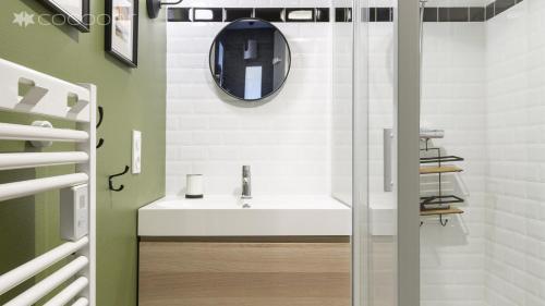 une salle de bain avec un lavabo et un miroir au mur dans l'établissement Le Phenix by Cocoonr, à Nantes