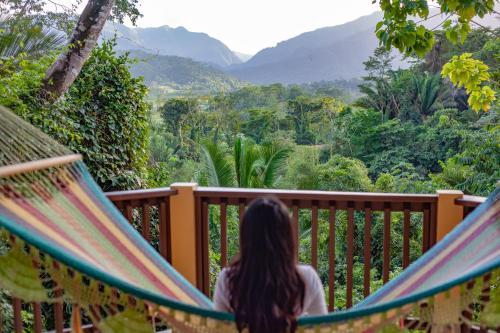 a woman sitting in a hammock looking at the mountains at Sleeping Giant Rainforest Lodge in Belmopan