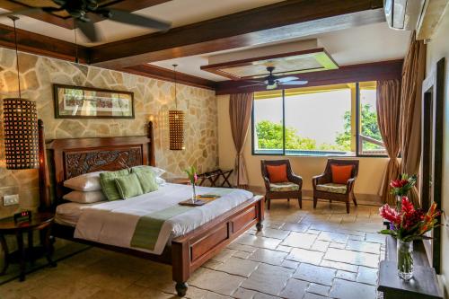 a bedroom with a large bed and two chairs at Sleeping Giant Rainforest Lodge in Belmopan