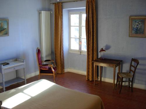 een slaapkamer met een bed, een bureau en een raam bij LE MAS DU CAPRIER in Charleval