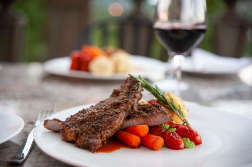 a plate of meat and vegetables with a glass of wine at IL Castello in Clarens