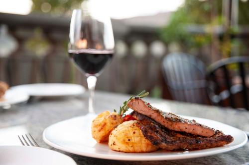 a plate of meat and potatoes with a glass of wine at IL Castello in Clarens