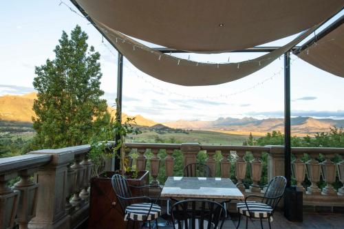 a table and chairs on a balcony with a view of mountains at IL Castello in Clarens