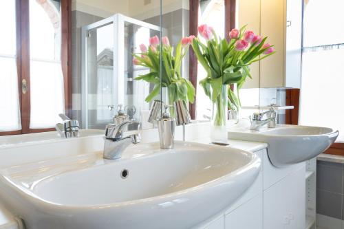 a bathroom with two sinks and two vases of flowers at Oasi Picolit in Povoletto