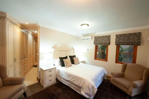 a bedroom with a white bed and two chairs at IL Castello in Clarens