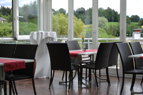 a dining room with a table and chairs and windows at Pension Karawankenblick in Moosburg