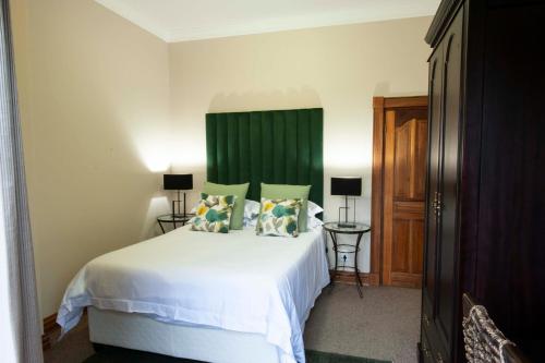 a bedroom with a white bed with a green headboard at IL Castello in Clarens