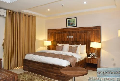 a bedroom with a large bed with a wooden headboard at Qualibest Grand Hotels in Abuja