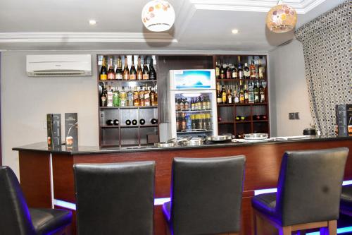 a bar with chairs and bottles of alcohol at Qualibest Grand Hotels in Abuja
