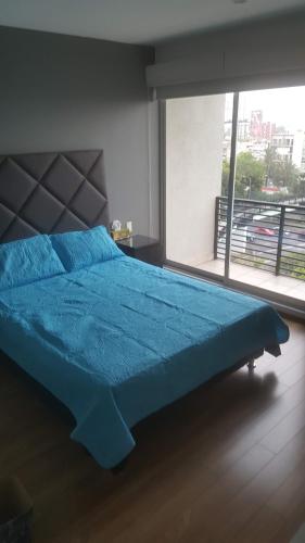 a blue bed in a bedroom with a large window at Division del Norte Rooms in Mexico City