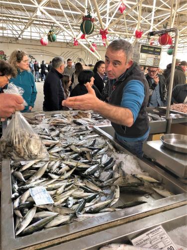 a man standing in front of a table of fish at Central Tavira apartment, Casa Oliverio in Tavira