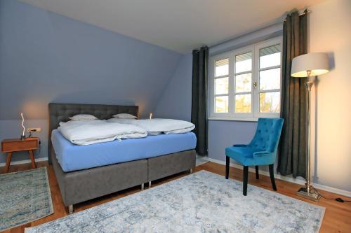 a bedroom with a bed and a blue chair and a window at Ferienwohnung im Blauen Haus in Ahrenshoop