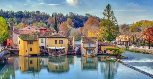 un pueblo en el agua con árboles coloridos en Il Borghetto Vacanze nei Mulini, en Valeggio sul Mincio