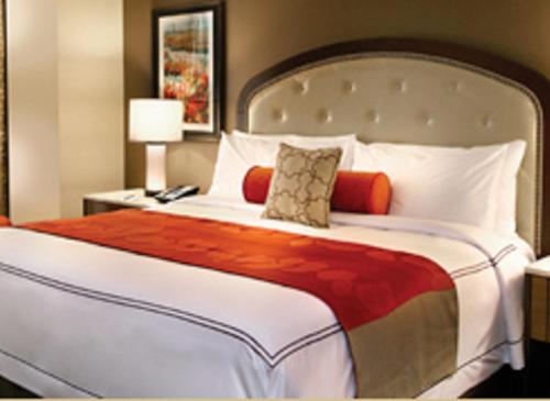 a bedroom with a large bed with a red and white blanket at L'Auberge Baton Rouge in Baton Rouge