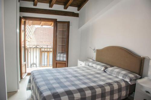 een slaapkamer met een bed met een geruite deken bij Ca' la Paz - Mogarraz in Mogarraz