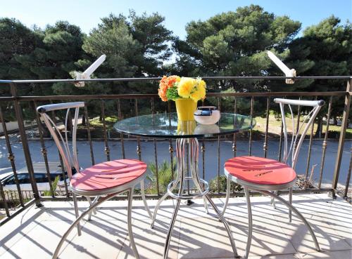 a glass table with two chairs and a vase of flowers at Hotel Iride by Marino Tourist in San Vito lo Capo
