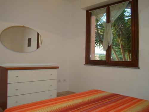 a bedroom with a bed and a mirror and a dresser at Appartamento Deledda in Muravera