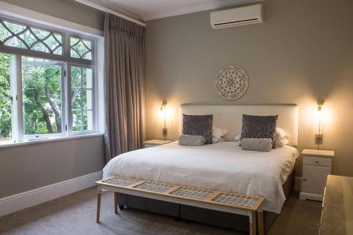 a bedroom with a large white bed and windows at Summerwood Guest House in Stellenbosch