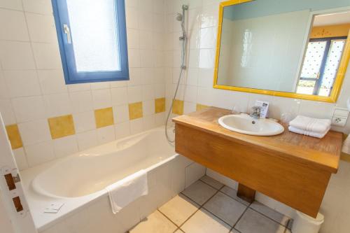 une salle de bain avec un lavabo, une baignoire et un miroir dans l'établissement auberge du golf, à La Roche-de-Glun