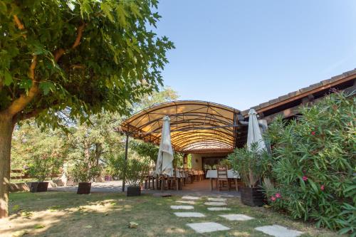 un patio avec des tables et des parasols dans un jardin dans l'établissement auberge du golf, à La Roche-de-Glun