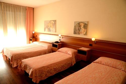 a hotel room with three beds and a window at Hotel HDomus in Nogarole Rocca