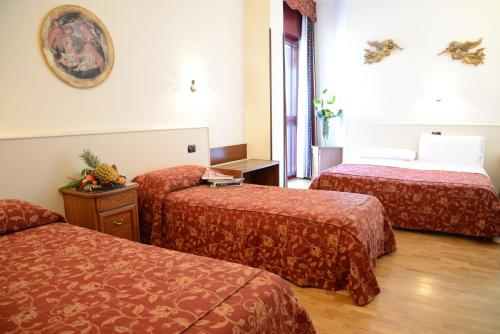 um quarto de hotel com duas camas com lençóis vermelhos em Hotel Da Franco em Nogarole Rocca
