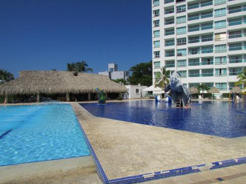 a swimming pool in front of a large building at Costa Azul Suites 403 in Santa Marta