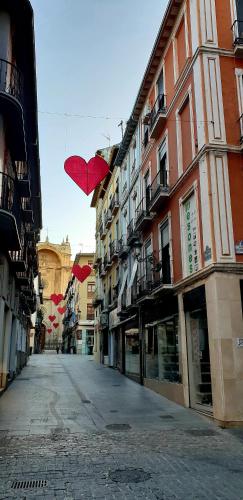 an empty street with red umbrellas hanging from buildings at Pension Mesones in Granada